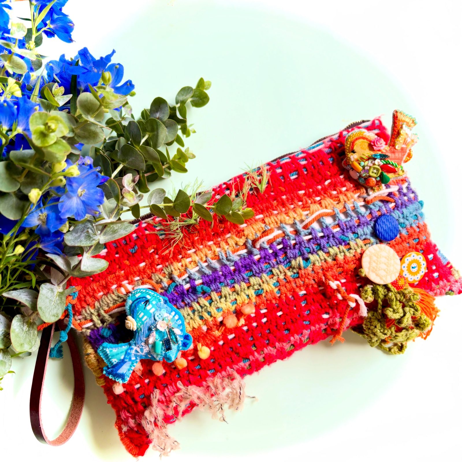 Red hand-crocheted clutch with rainbow stripes, decorated with real dried flowers and beads