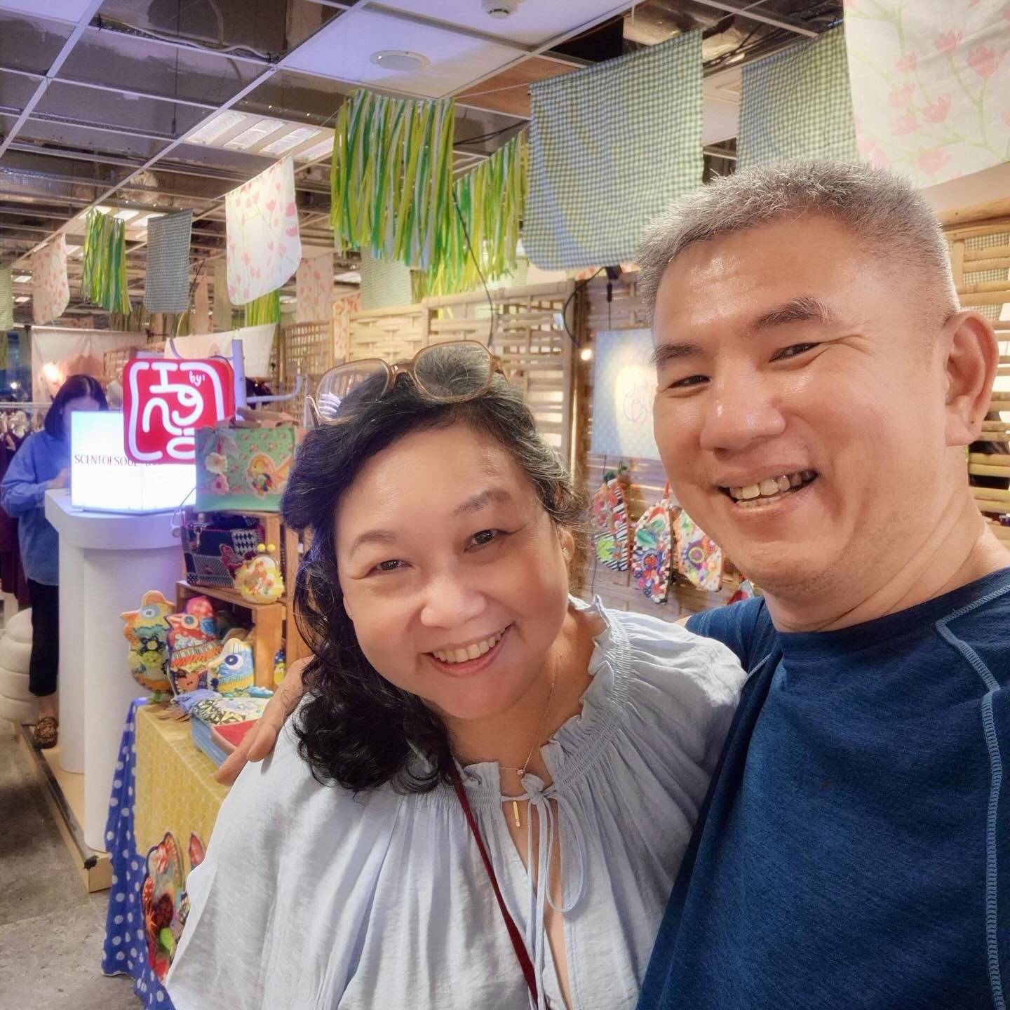 Igna Najoan smiling at her market stall, pieces hanging behind her