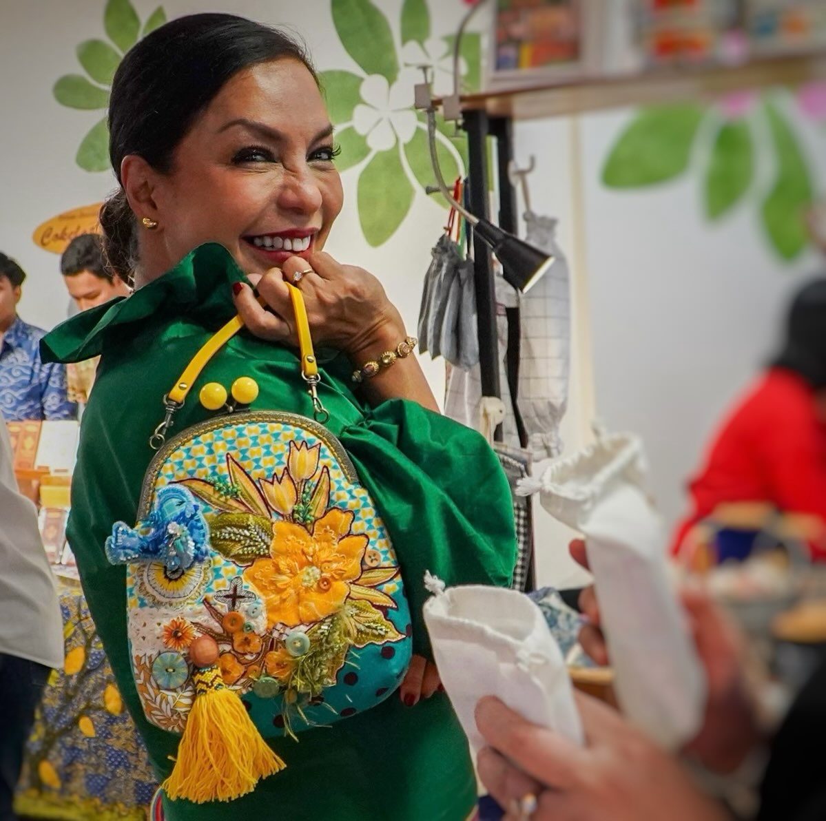 A customer holding up a yellow sunflower embroidered bag at the stall